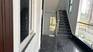 A modern interior with a staircase leading to an upper floor, a balcony with a view of construction outside, and a polished black marble floor. - Independent floor for rent in Hyderabad (Hayathnagar_Khalsa)