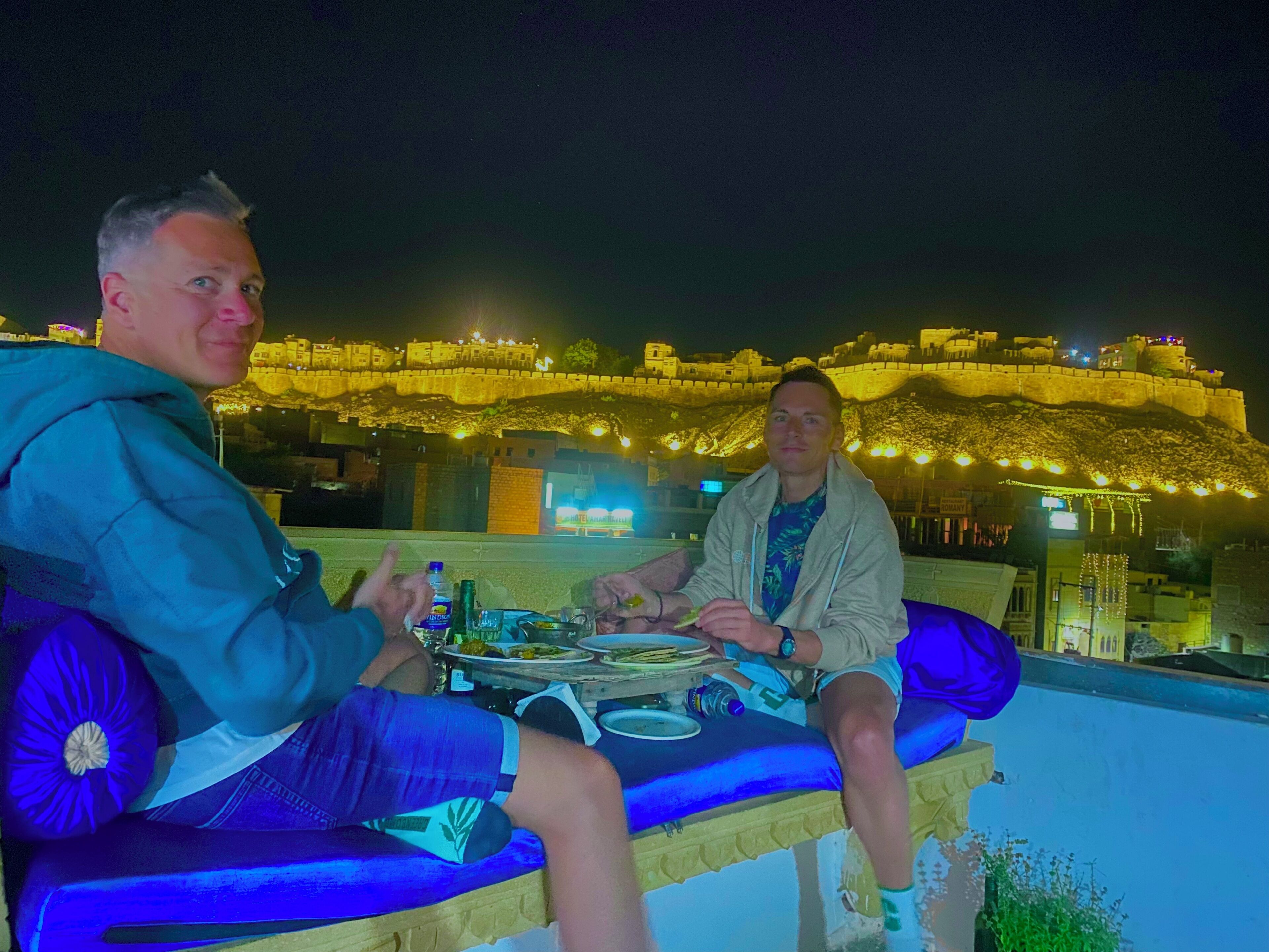 Deux personnes sont assises sur un balcon d’où l’on peut admirer un ancien fort.