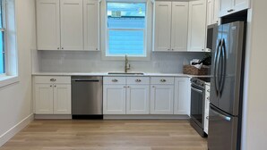 A modern kitchen with white cabinetry, stainless steel appliances, and a window above the sink. - Charming 2-bedroom guesthouse in peaceful Gladstone with WiFi, AC (Gladstone)
