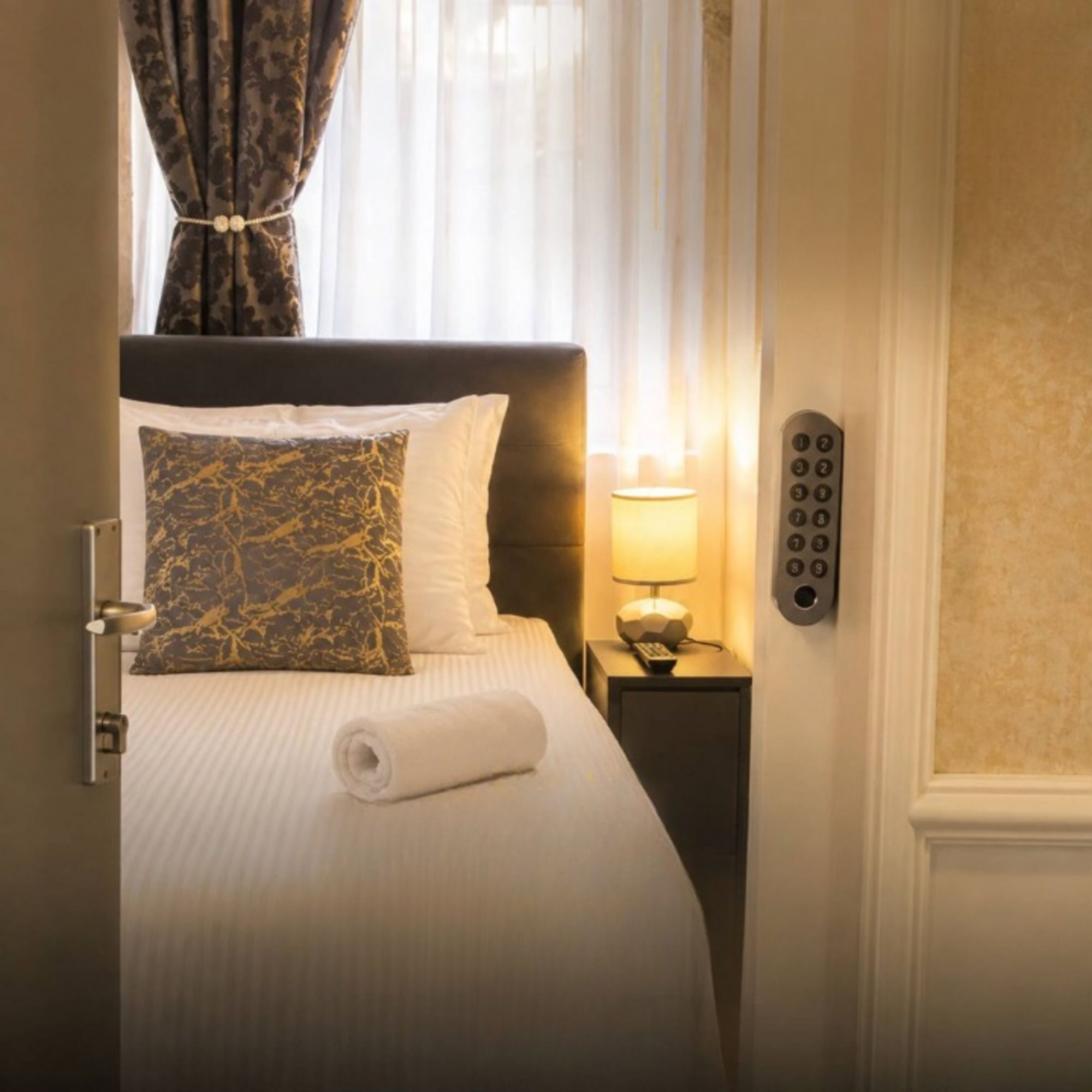 A hotel room with a bed, a nightstand with a lamp, and a telephone.