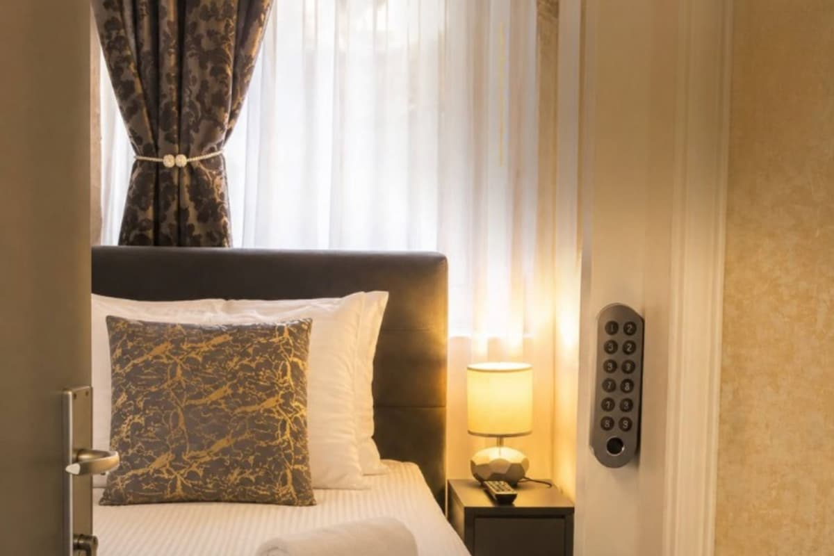 A hotel room with a bed, a nightstand with a lamp, and a telephone.