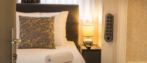 A hotel room with a bed, a nightstand with a lamp, and a telephone.