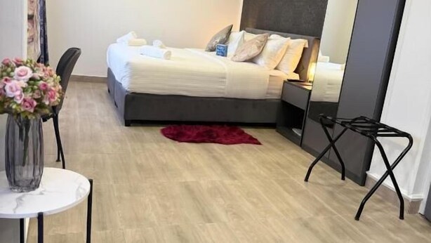 A modern hotel room with a bed, a desk, a chair, a mirror, and a TV on the wall. - Alsago Lux (Sesvete)