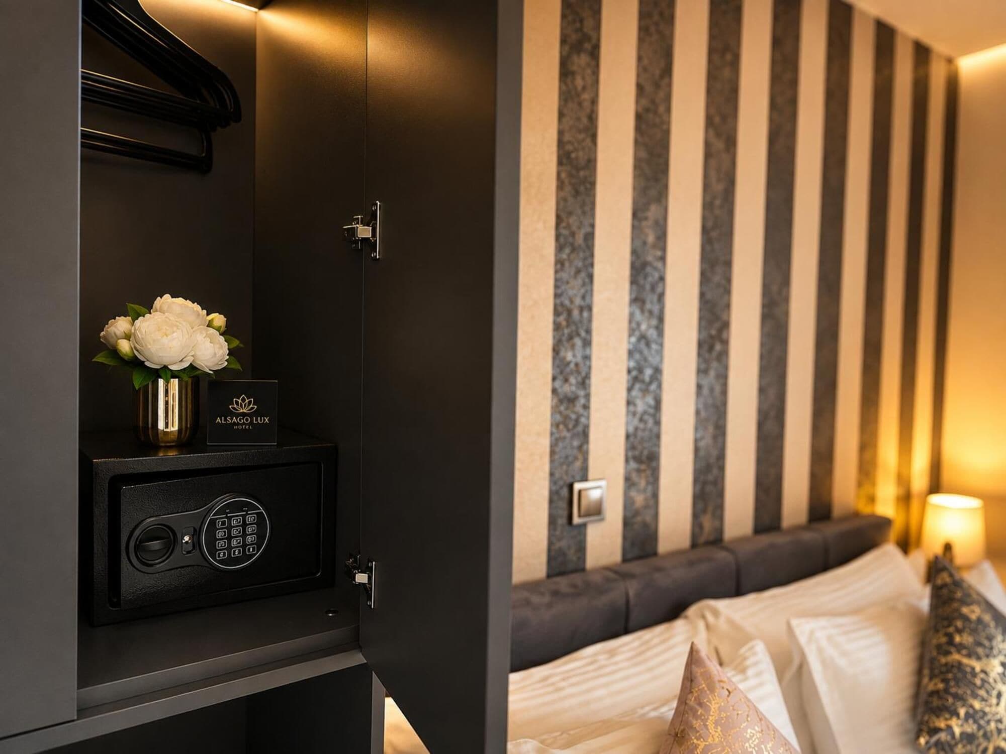 Una habitación de hotel con una cama, una caja fuerte y una pared con rayas verticales.