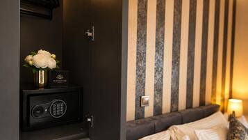 Una habitación de hotel con una cama, una caja fuerte y una pared con rayas verticales.