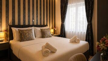 A hotel room with a large bed, two bedside tables, a desk, and a window with curtains.