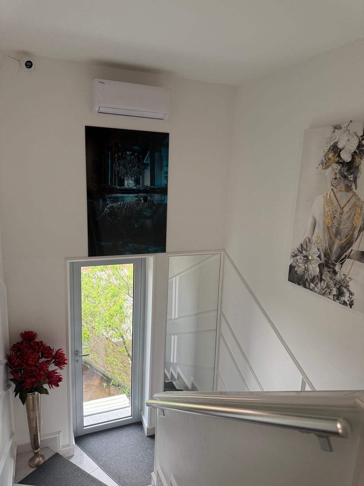 Un intérieur moderne avec un escalier, une porte donnant sur l’extérieur et un climatiseur fixé au mur.