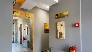 Un pasillo moderno con un extintor, una cámara de seguridad y un cartel que indica la ubicación.