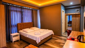Una habitación de hotel moderna con cama, mesita de noche y zona de escritorio.