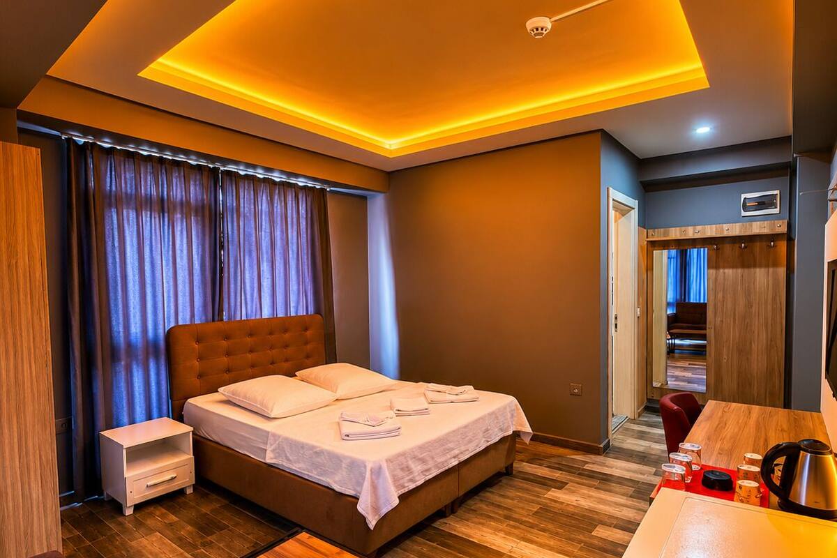 A modern hotel room with a bed, bedside table, and a desk area.