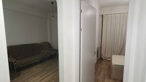 Una habitación con sofá, cama y una puerta que da a otra estancia.