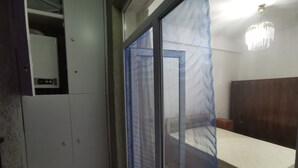 Un dormitorio con cama, armario y puerta corredera con mosquitera azul.