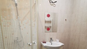 Un baño con ducha envuelta en vidrio, un lavabo con espejo y un inodoro.