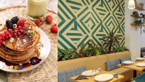 Une table mise pour le petit-déjeuner avec des crêpes et des fruits rouges, un mur décoré de motifs et un coin repas avec des tables et des chaises.