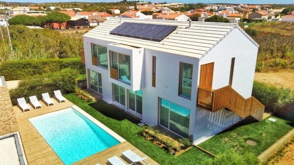 Una casa moderna de dos pisos con piscina, ventanas amplias y un panel solar en el techo.