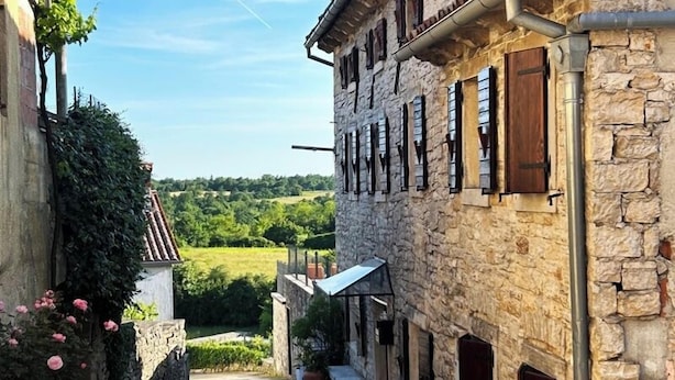 A narrow street flanked by stone buildings with wooden shutters, a bench, and a small garden area. - Villa Annette with Pool - Istriensonne 0784 (Zminj)