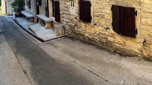 A stone building with multiple windows and shutters, a small porch with benches, and a clear sky in the background. - Villa Annette with Pool - Istriensonne 0784 (Zminj)