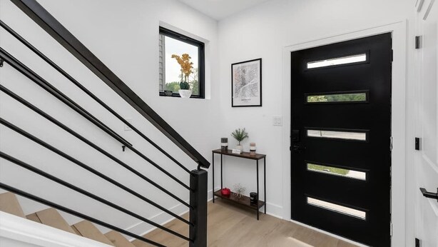 En modern inredning med en trappa, en svart dörr med glaspaneler, ett litet bord med dekorativa föremål och en inramad karta på väggen.