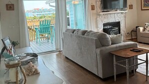 Un salon avec un canapé, une cheminée, un téléviseur et une vue sur l’extérieur.
