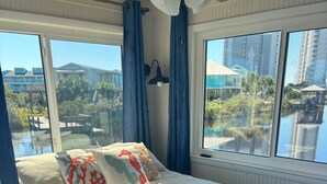 Une chambre avec un grand lit, une vue sur un plan d’eau et un paysage urbain en arrière-plan.