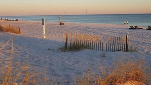 Une plage de sable, une clôture et quelques personnes au loin.