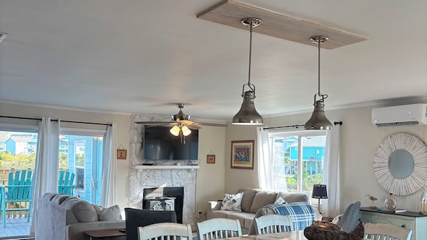 Un vaste espace de vie comprenant un grand îlot central, une cheminée et un ventilateur de plafond.