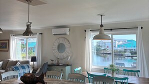 Une cuisine spacieuse dotée d’un grand îlot central, d’un coin repas avec des chaises de couleur turquoise et d’une vue sur le bord de l’eau.