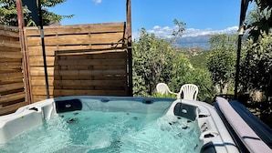 A hot tub with a wooden fence and chairs, surrounded by greenery and a mountain view. - Studio room with jacuzzi and heated swimming pool 4X8 (Alata)