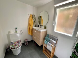 Ein kleines Badezimmer mit Toilette, Waschbecken, Spiegel und Fenster.