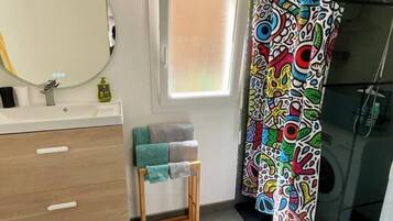 A bathroom with a white sink, a mirror, a wooden vanity, a towel rack, and a colorful shower curtain.