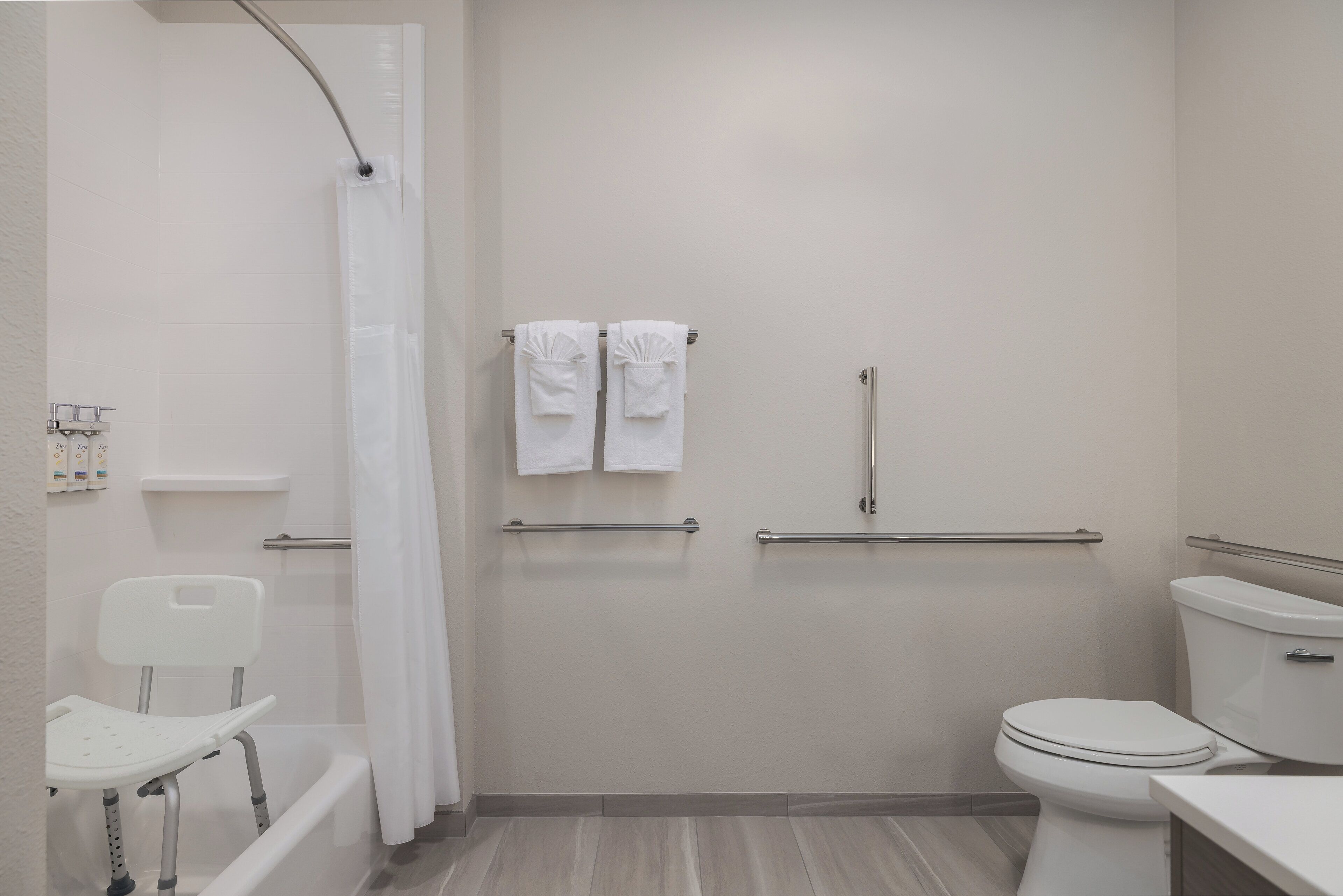 Une salle de bain équipée d’une douche, de toilettes et d’une barre d’appui.