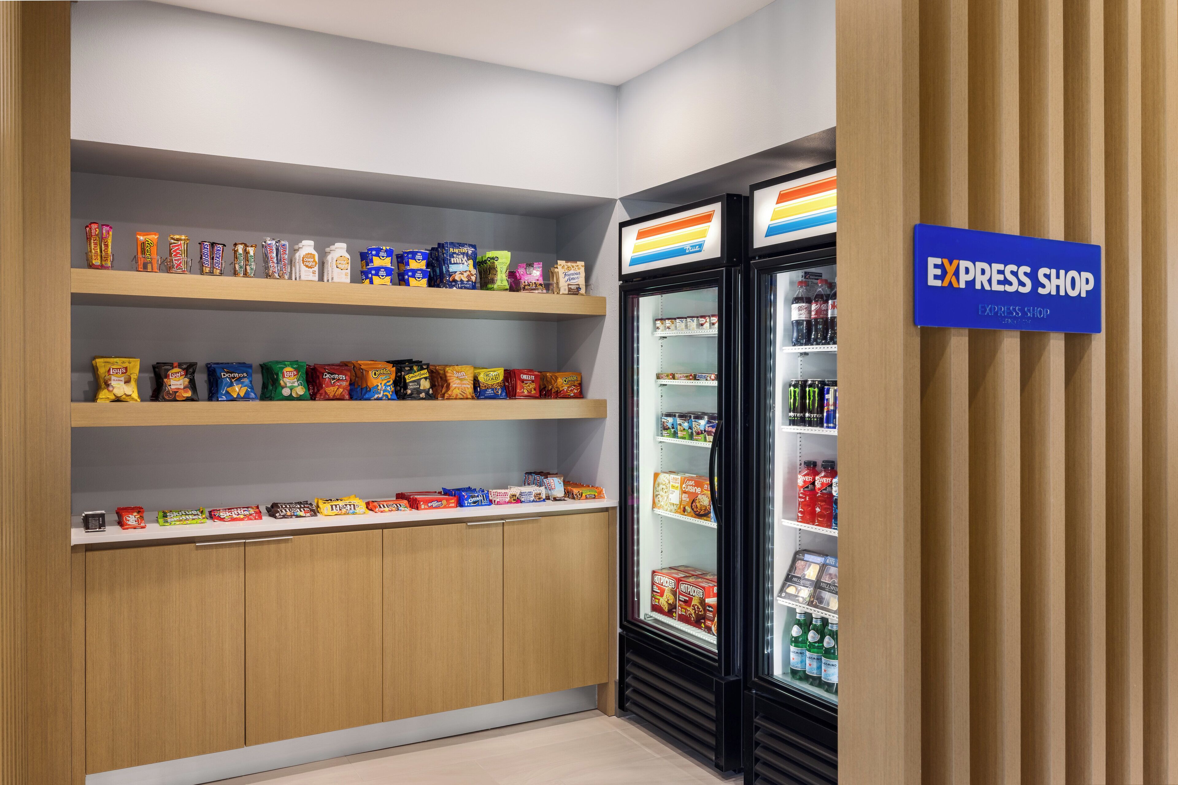 A snack and beverage display in a store with shelves stocked with various snacks and a refrigerated section with drinks.