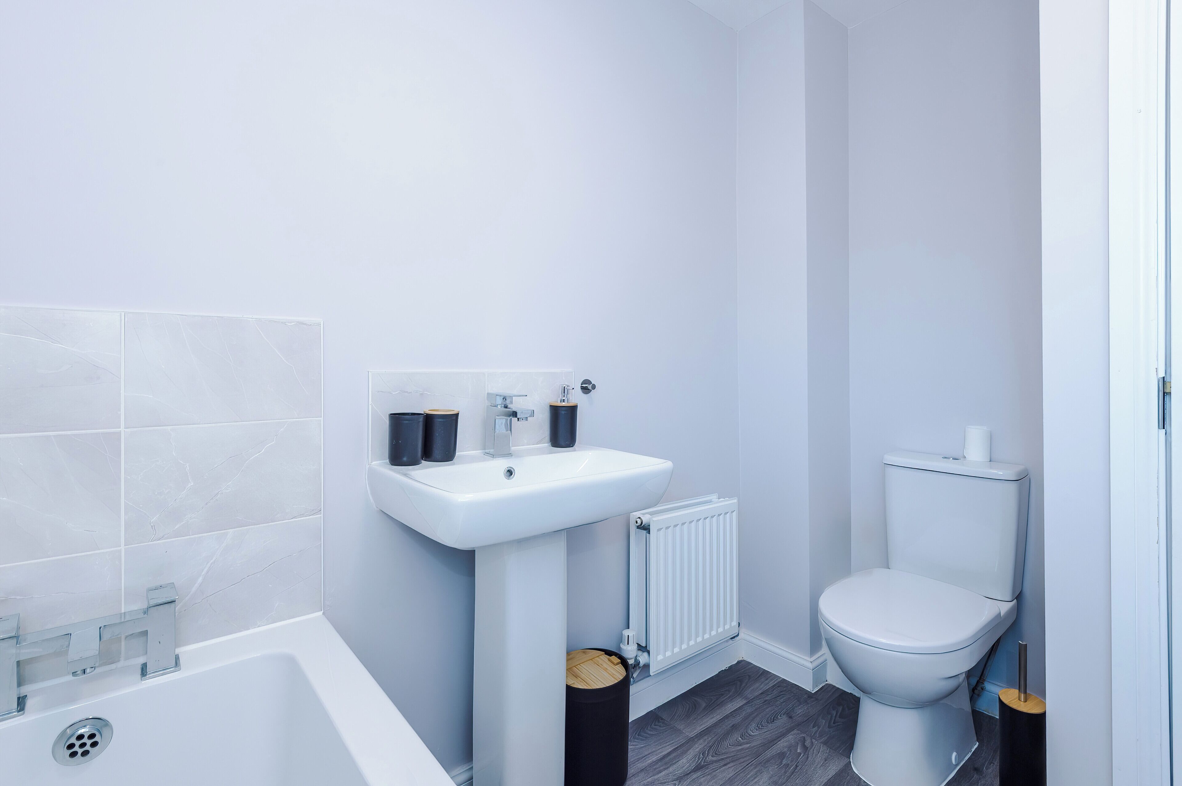 A modern bathroom with a white sink, toilet, and bathtub.