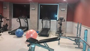 Ein Fitnessraum mit Laufbändern, Rudergerät, Langhantelbank und Trainingsbällen.