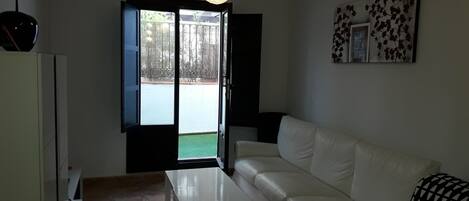 A living room with a white sofa, a white table, and a hanging light fixture.