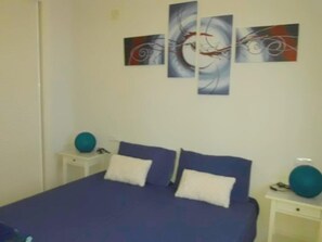 Ein Schlafzimmer mit einem Bett, zwei Kissen, einem Nachttisch und einem Wandbild.