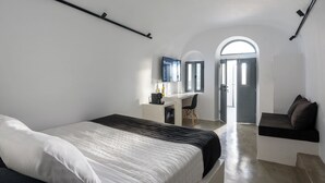 A modern bedroom with a large bed, a desk, and a television.