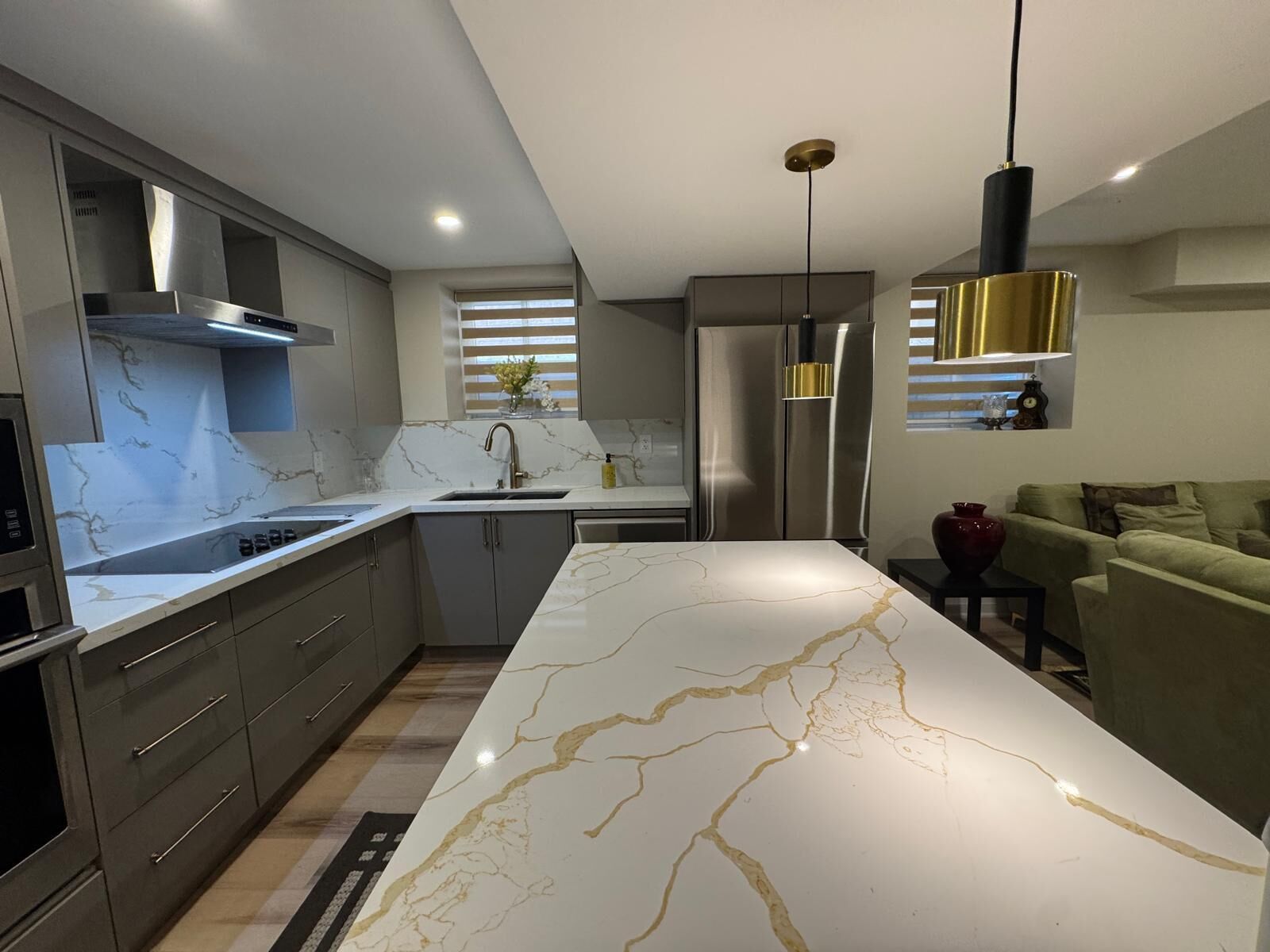 A modern kitchen with a marble island, stainless steel appliances, and a pendant light.