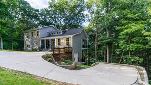A two-story house with a covered front porch, a landscaped front yard, and a driveway curving around the property.