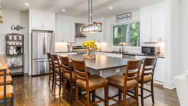 A modern kitchen with a central island, white cabinetry, and a coffee station.