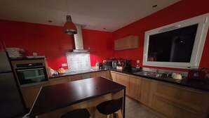 A compact kitchen with a central island, wooden cabinets, a microwave, and a built-in oven.