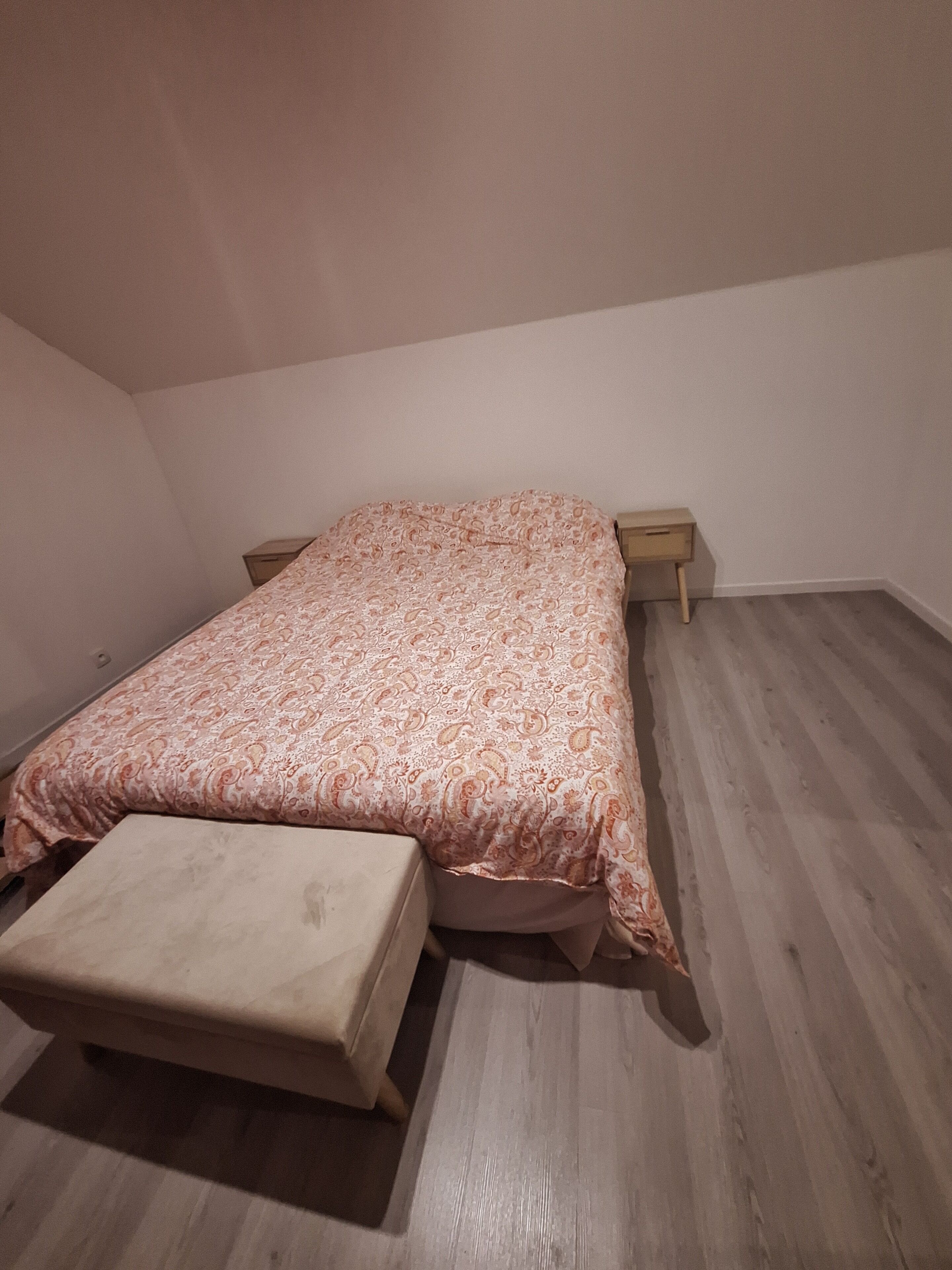 Una camera da letto con un letto, un comodino e una panca.