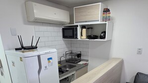 Een moderne keuken met witte kastjes, een ingebouwde magnetron, een koelkast en een houten aanrecht.