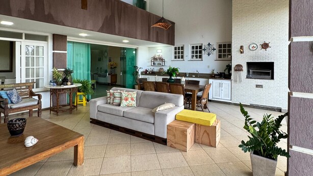 A spacious living area with a high ceiling, wooden beams, a sofa, a dining table, and a kitchen in the background. - SEASONAL RENTAL BEACH HOUSE ARACAJU SERGIPE CLOSED CONDO FRONT OF THE SEA (Mosqueiro Aracaju)