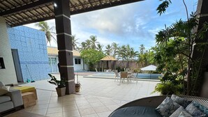 A covered outdoor seating area with a pool, lounge chairs, and a dining table. - SEASONAL RENTAL BEACH HOUSE ARACAJU SERGIPE CLOSED CONDO FRONT OF THE SEA (Mosqueiro Aracaju)
