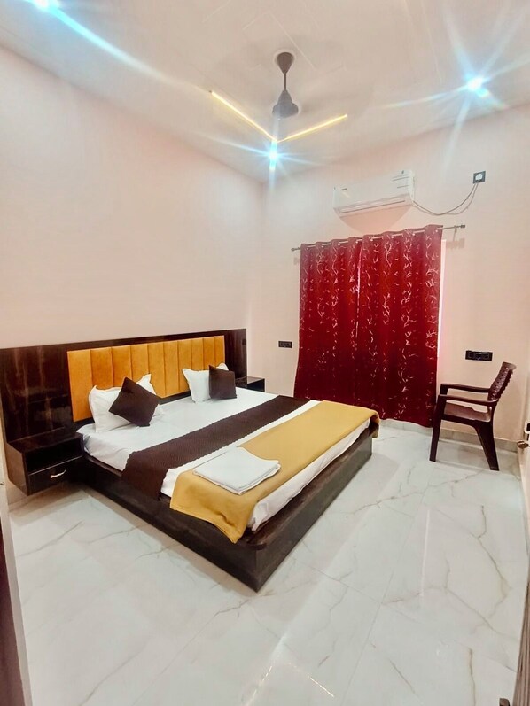 A bedroom with a bed, a nightstand, a chair, a red curtain, and an air conditioning unit.