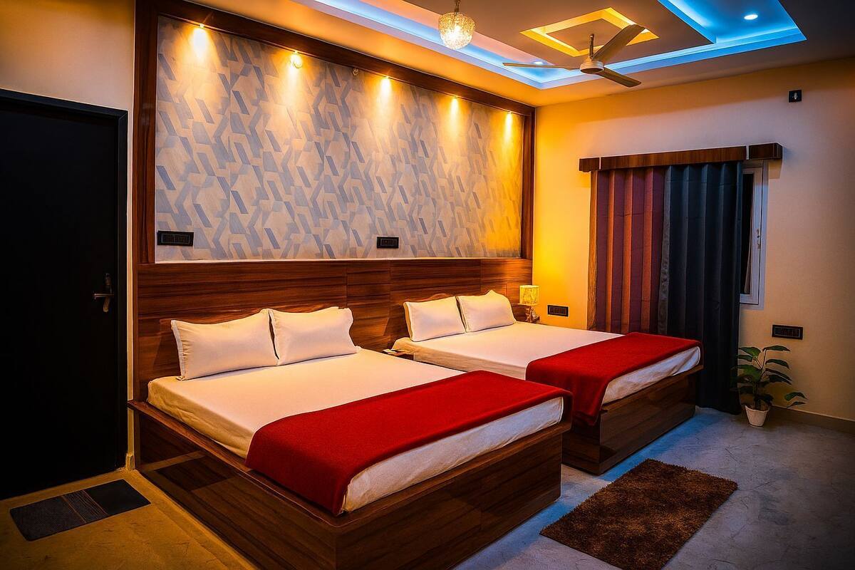 A hotel room with two beds, a ceiling fan, and a modern light fixture.