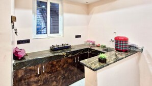 A modern kitchen with a marble countertop, built-in cabinets, a gas stove, and a window with a view. - Krishnam Niwas Near Ram temple Ayodhya  (Faizabad)