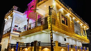 A multi-story building with balconies and string lights. - Krishnam Niwas Near Ram temple Ayodhya  (Faizabad)