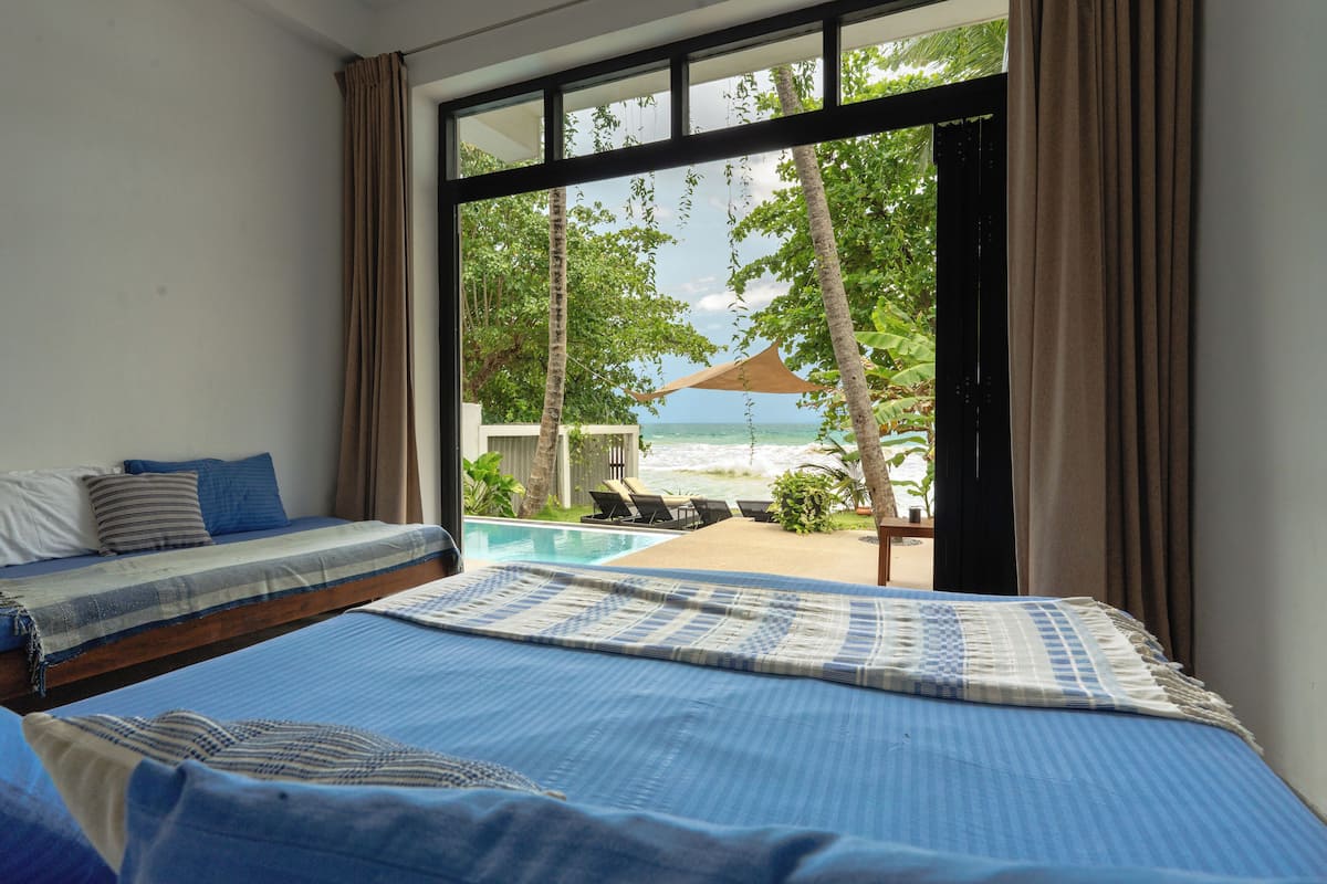 A bedroom with a view of a pool and beach.